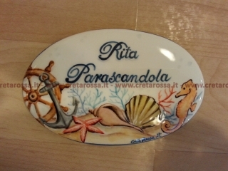 cod.art: nc66 - Mattonella in ceramica ovale 8,5x13 circa con motivi marini e scritta personalizzata. 